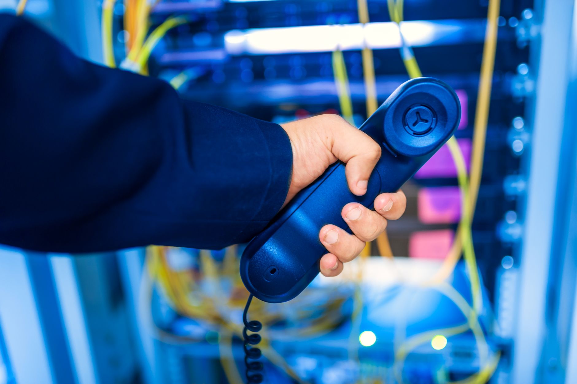 Hånd med telefonrør foran et serverrack