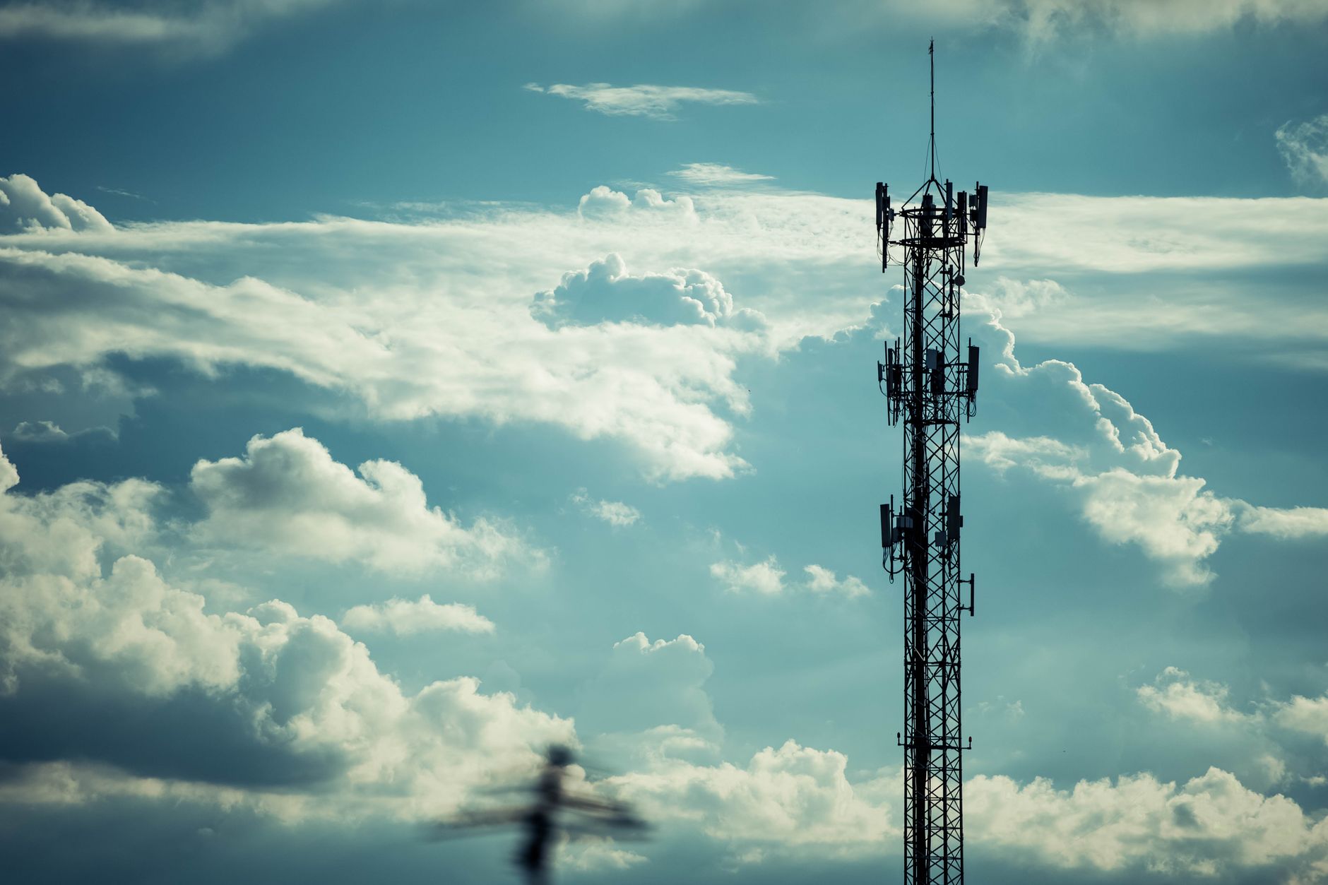 Mobilmast med antenner set mod en lys himmel